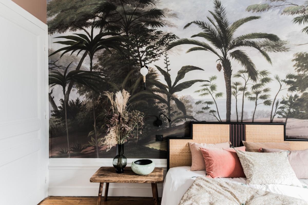 Chambre avec papier peint tropical. Les éléments sont en bois et dans des couleurs naturelles afin de créer une ambiance nature.